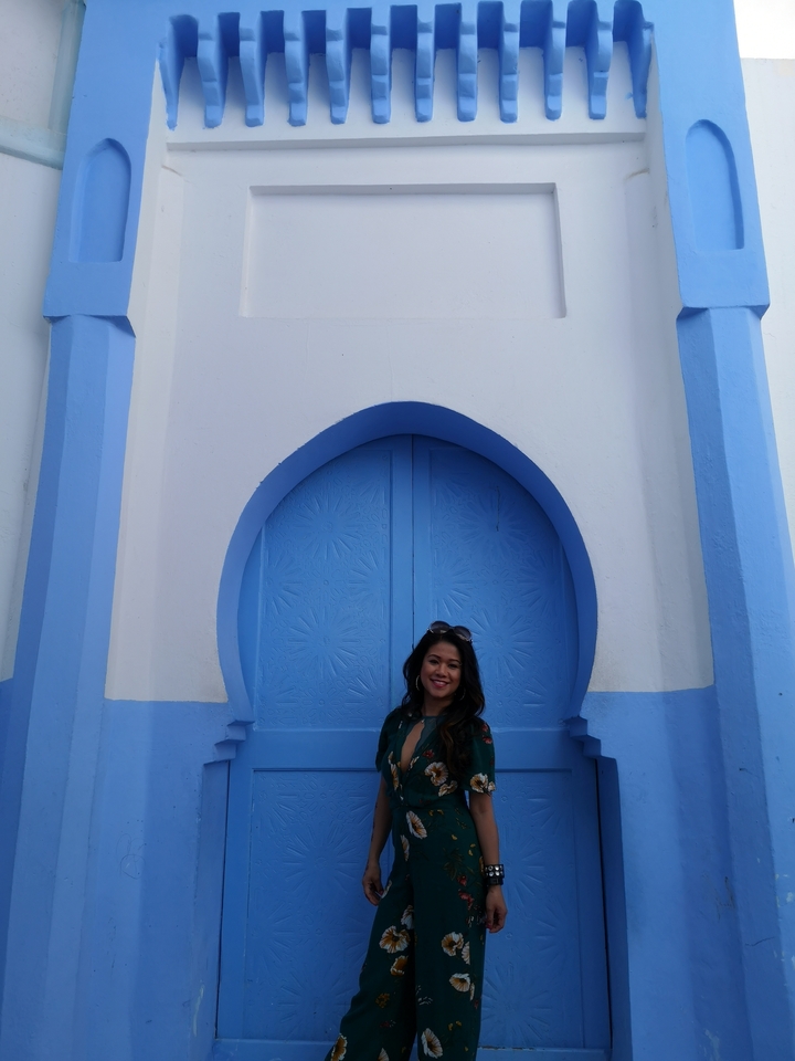 Person standing in front of a blue arched door.
