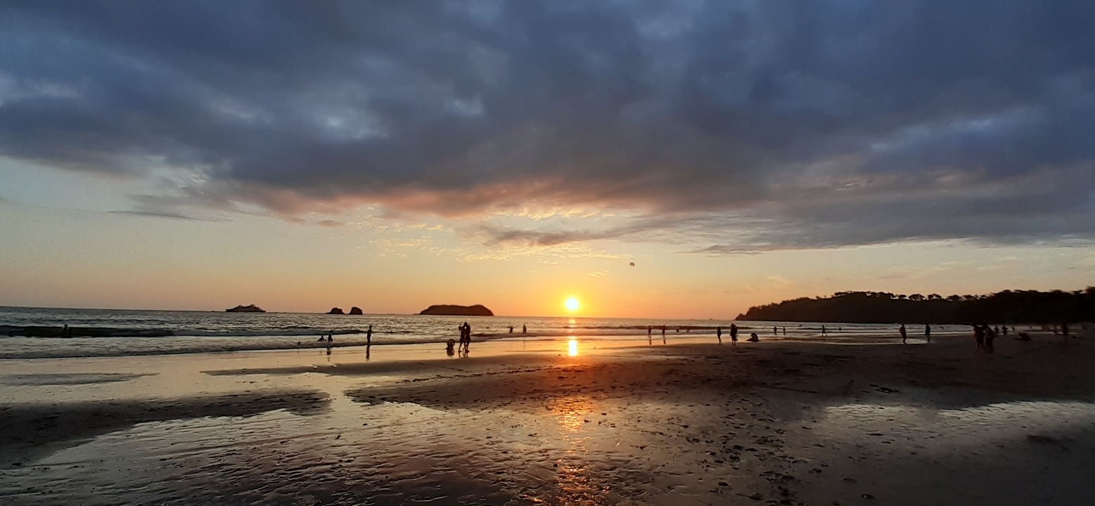 Sunset on a beach with people in the distance.