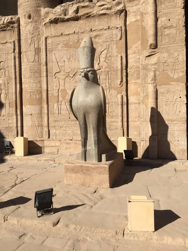 Ancient Egyptian statue and carvings on temple wall.