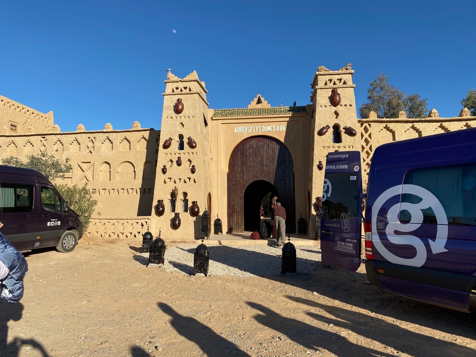 Entrance to a desert fort with tourists and vehicles.