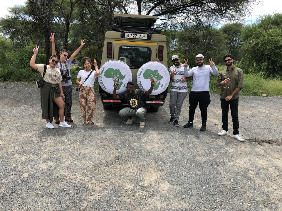 Groupe de personnes posant devant un véhicule de safari.
