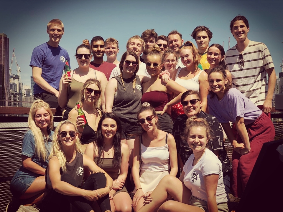Large group of people posing for a photo with an urban backdrop.