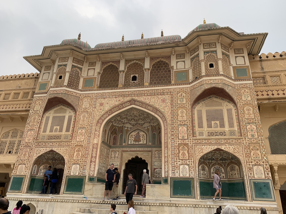 Elaborate facade of an Indian palace with people at the entrance.