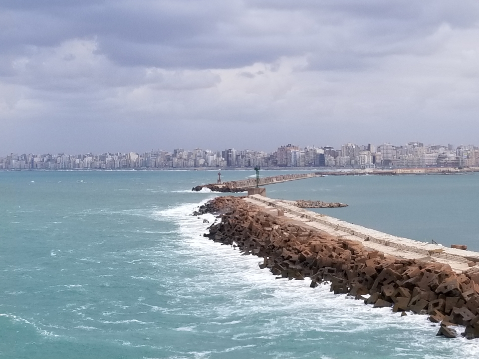 Coastal cityscape with a breakwater leading out to sea.