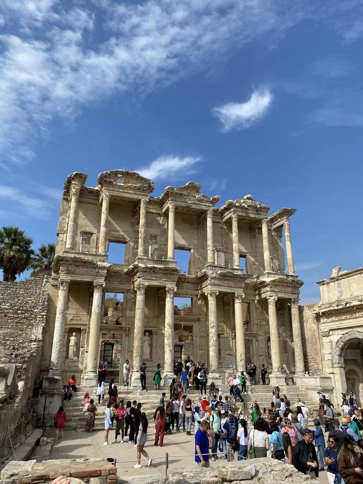 The ruins of an ancient library facade with tourists around.