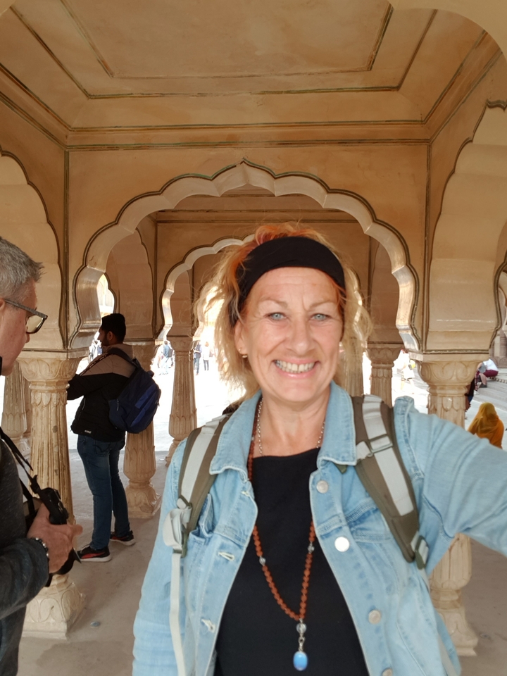 Person smiling with architectural arches in the background.
