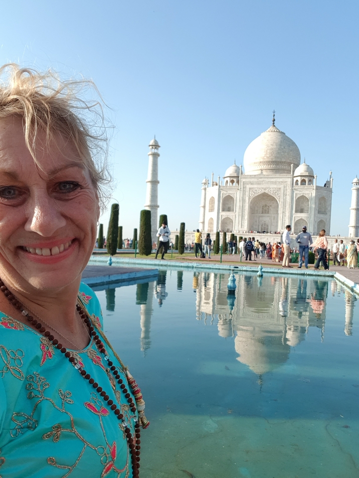 Woman posing in front of the Taj Mahal reflection pool.