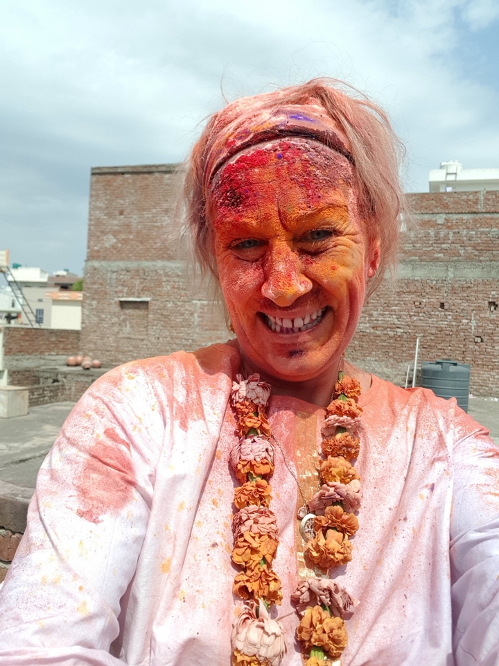 Person with face covered in orange powder during a festival.
