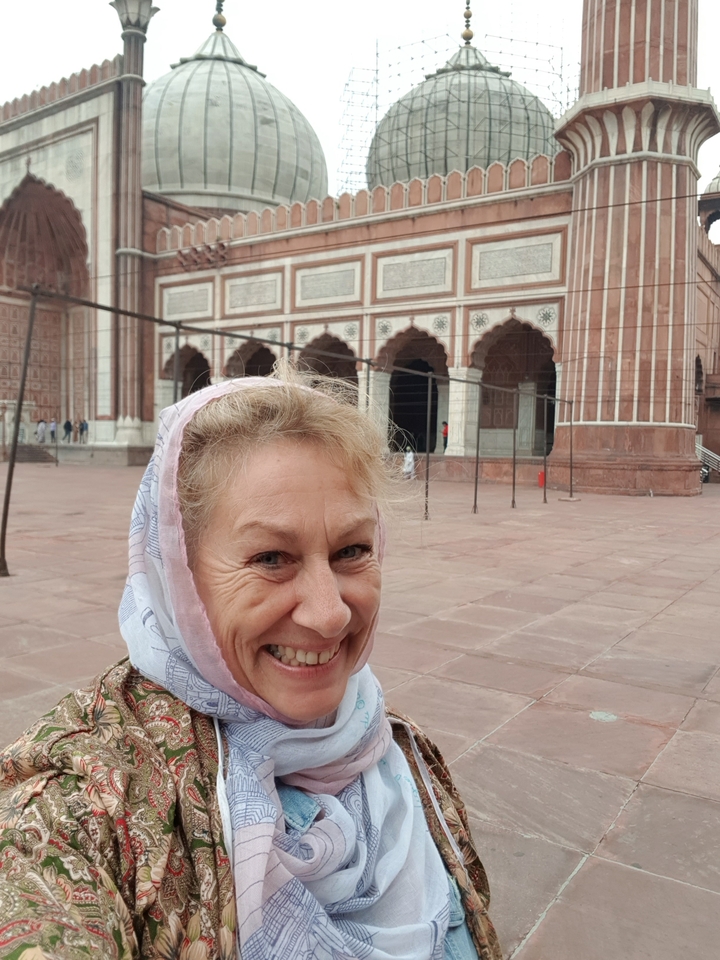 Person in headscarf standing in front of a large red fort.