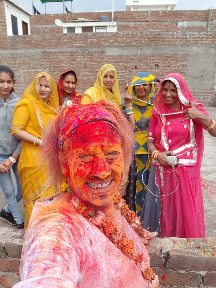 Group of women in traditional attire celebrating with colors.