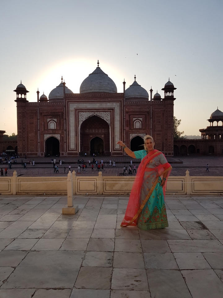 Woman posing in traditional attire in front of a historical red building.