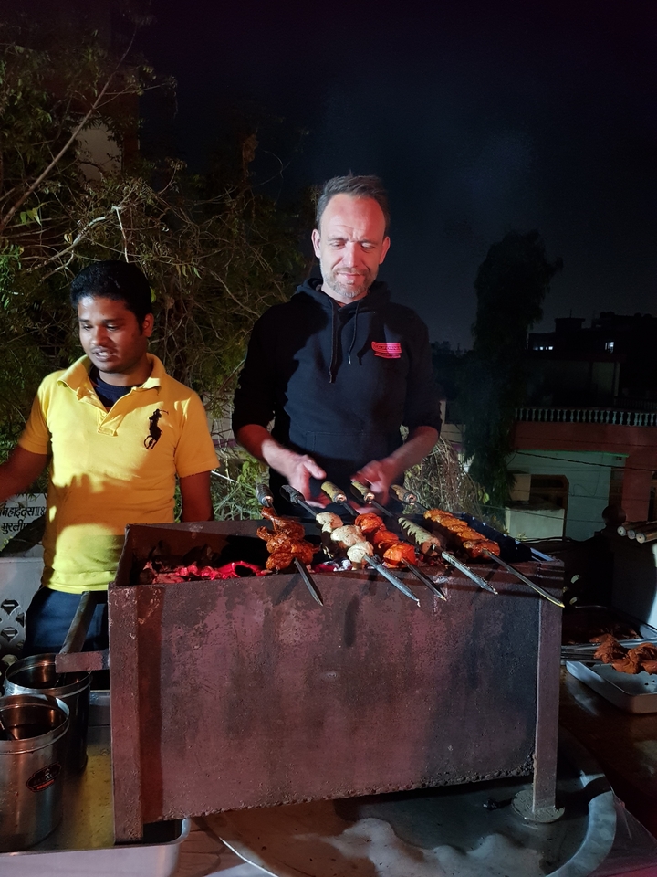 Two men grilling skewers at night.