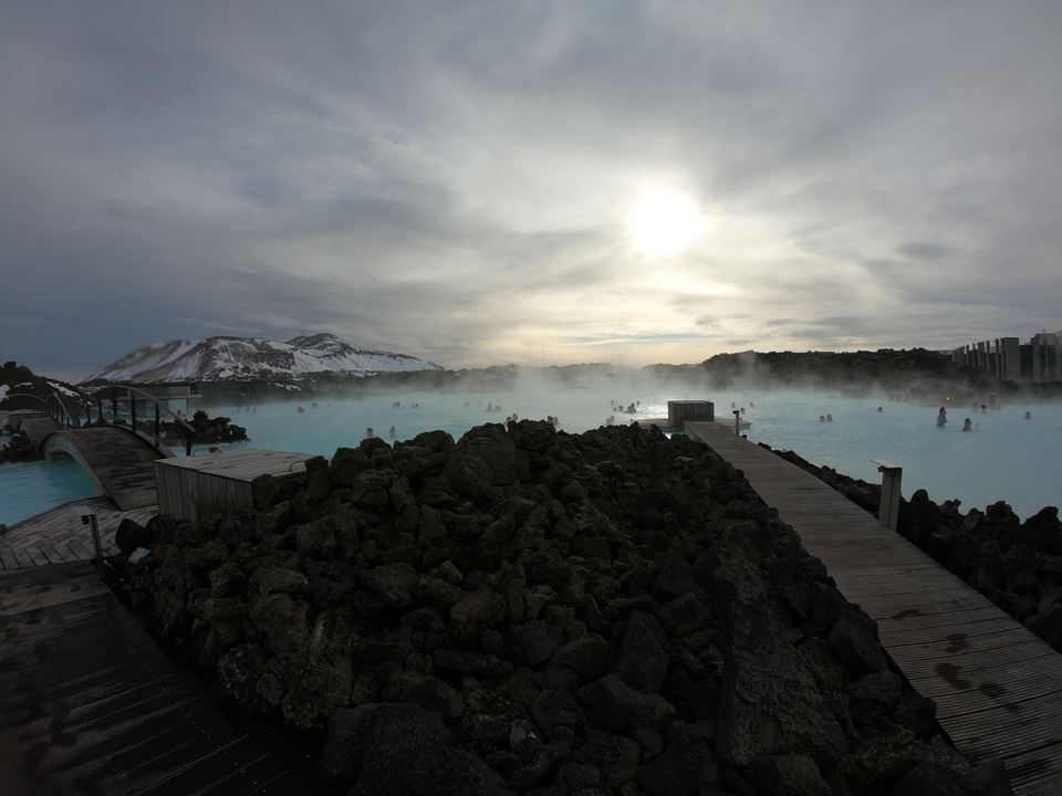 Hot springs with people bathing and snowy mountains.