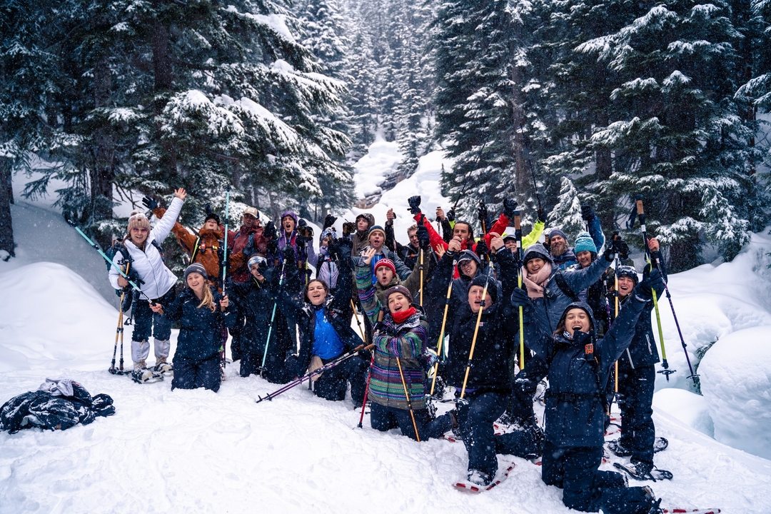 Group of people posing with ski poles in a snowy forest.