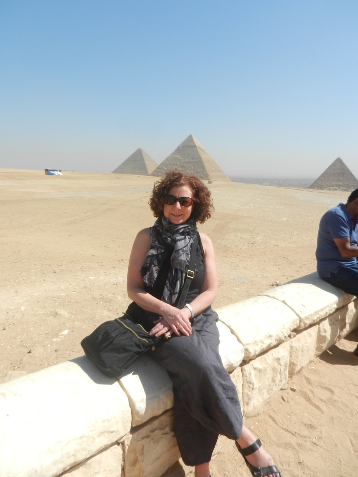 A woman seated with pyramids visible in the background.