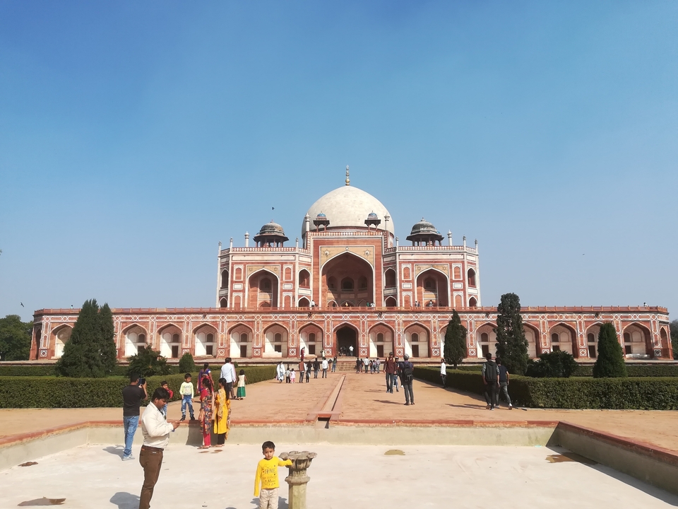 Tourists visiting Humayun's Tomb, a historical site with a large dome and gardens.