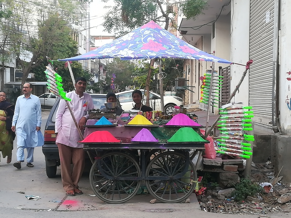 Vendors with colorful powders for sale at a street market.