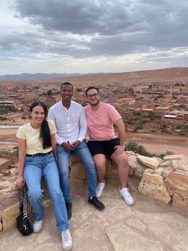 Three people posing on a rocky outcrop overlooking the town