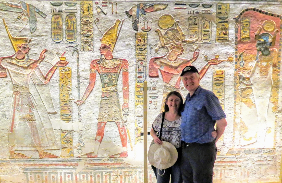 Couple posing in front of a wall with Egyptian hieroglyphs and carvings.