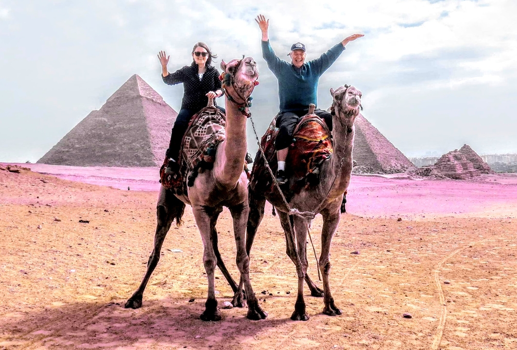 Couple riding camels near the pyramids of Giza.