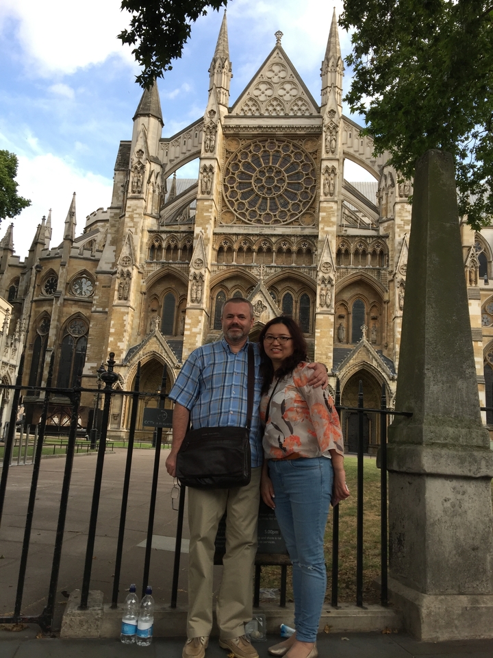 A couple posing in front of a grand gothic building.