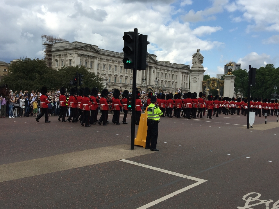 A parade of guards in red attire in front of a grand palace.