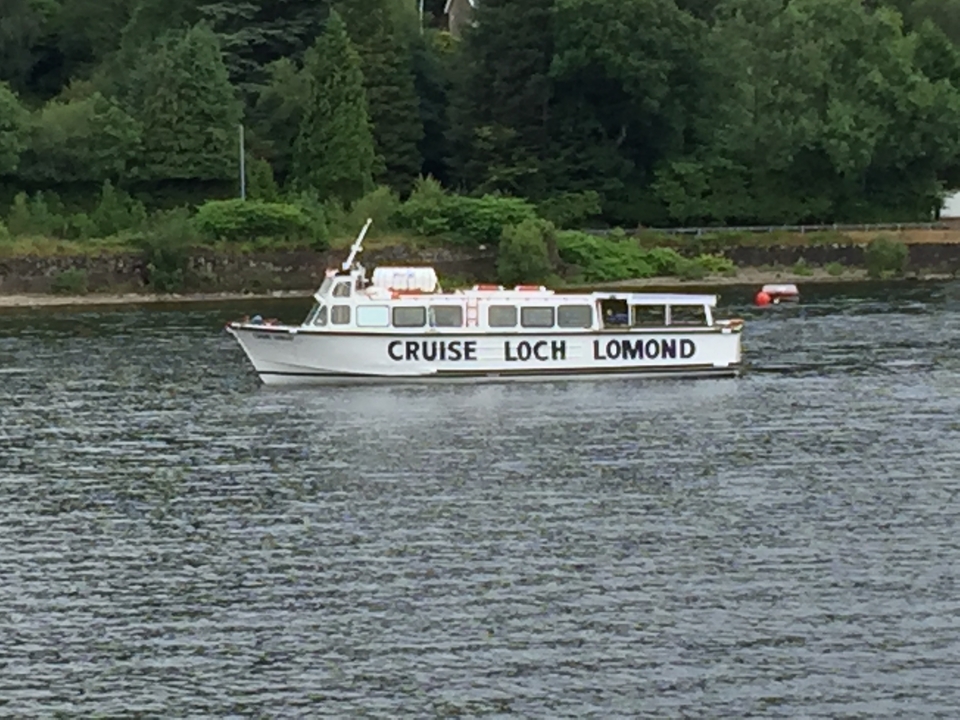 A cruise boat on a lake with a forested shore.