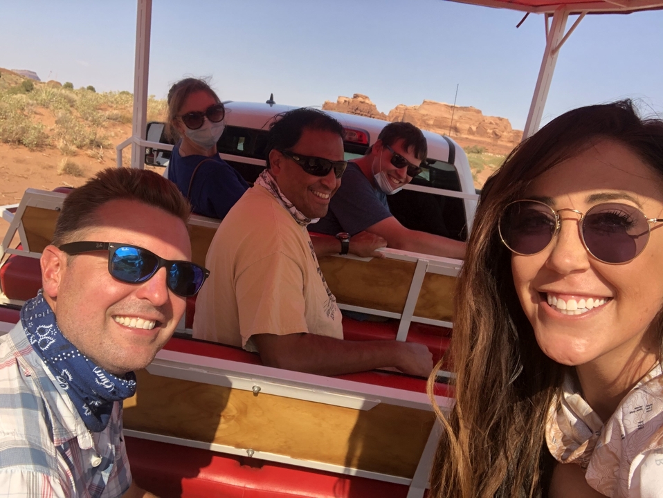 Group selfie in a vehicle with desert backdrop.