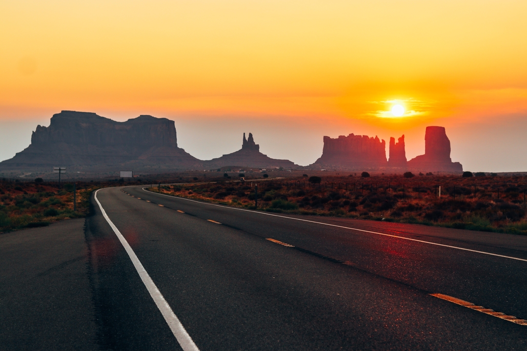 Sunset view over road leading to rock formations.