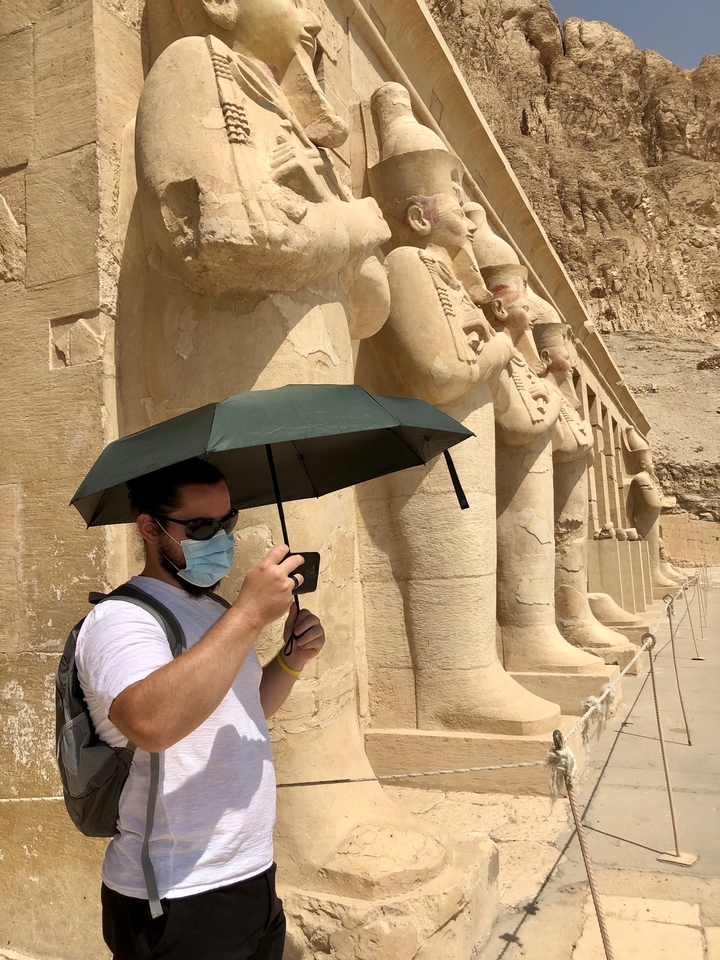 Person with umbrella in front of ancient pillars