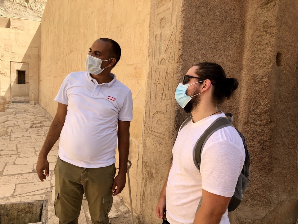 Two people standing next to ancient carvings