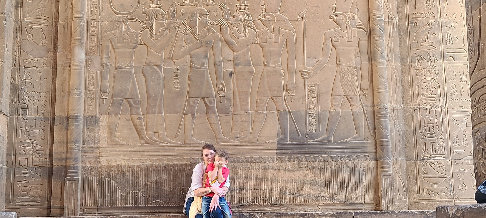 People sitting in front of ancient Egyptian wall carvings.
