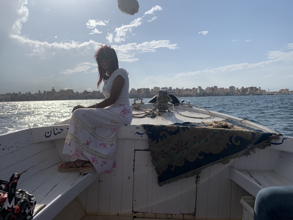 Personne assise sur un bateau avec un paysage urbain en arrière-plan.