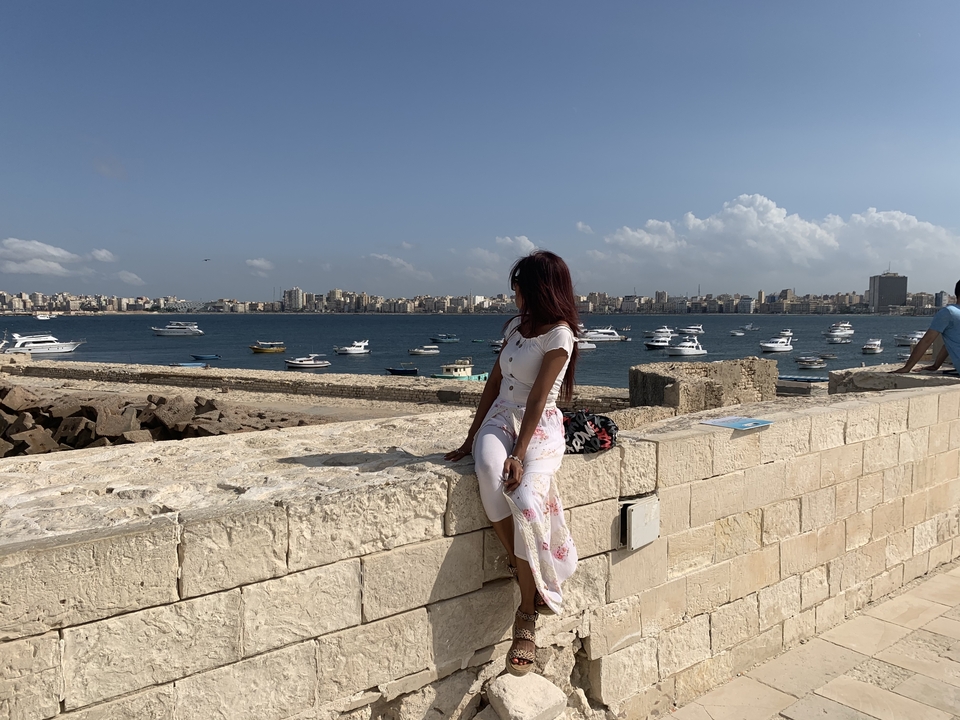 Personne assise sur un mur avec vue sur la mer et la ville d'Alexandrie.