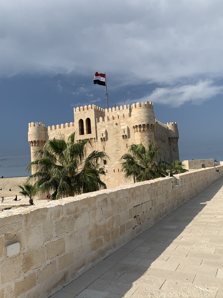 Fort Qaitbay à Alexandrie avec des palmiers.