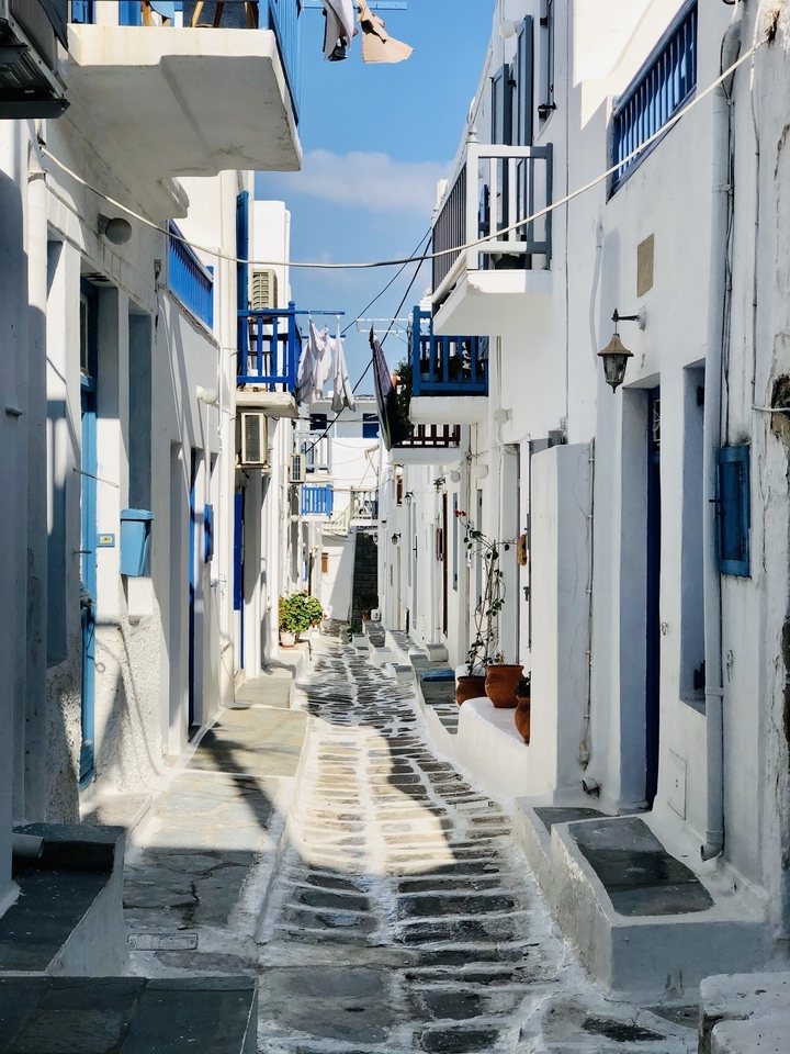 Narrow stone-paved street with whitewashed buildings in Mykonos.