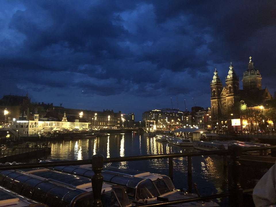Night scene of a cityscape with illuminated buildings and a waterway.