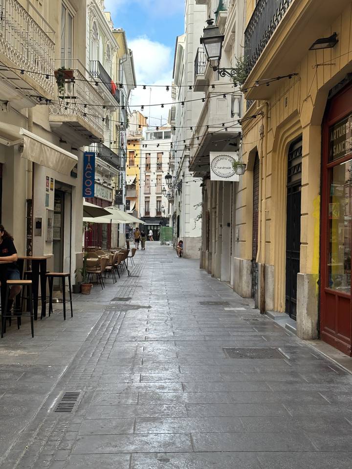 Narrow city street lined with shops and cafes.