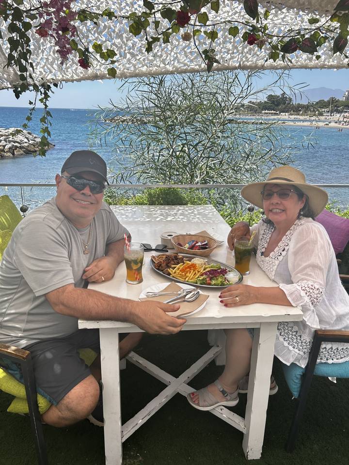 Couple dining by the sea with mixed dishes.