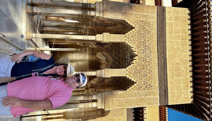 Man posing in front of intricate stone carvings.