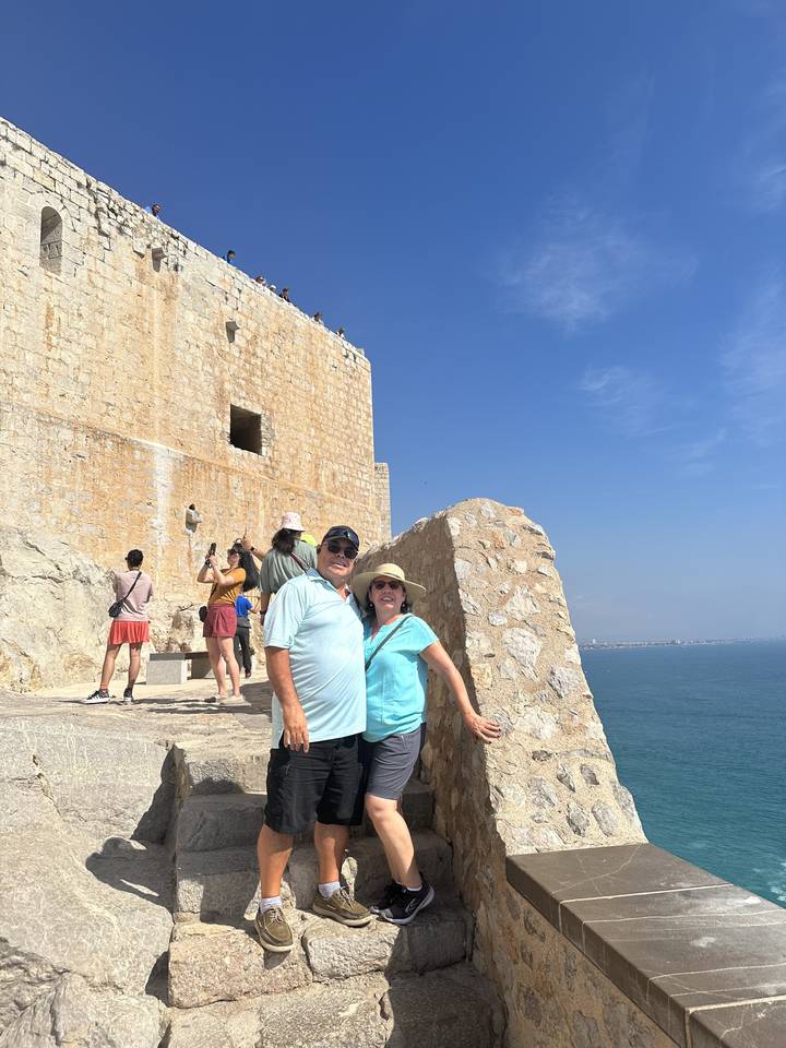 Couple on castle ruins overlooking a vast seascape.