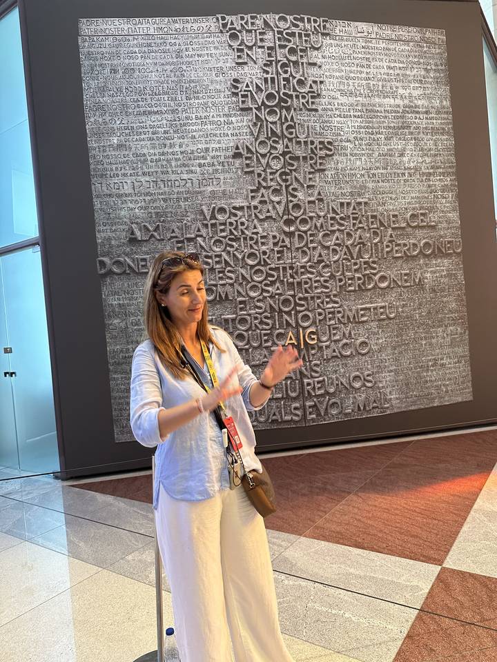 Tour guide explaining content in front of a wall plaque.