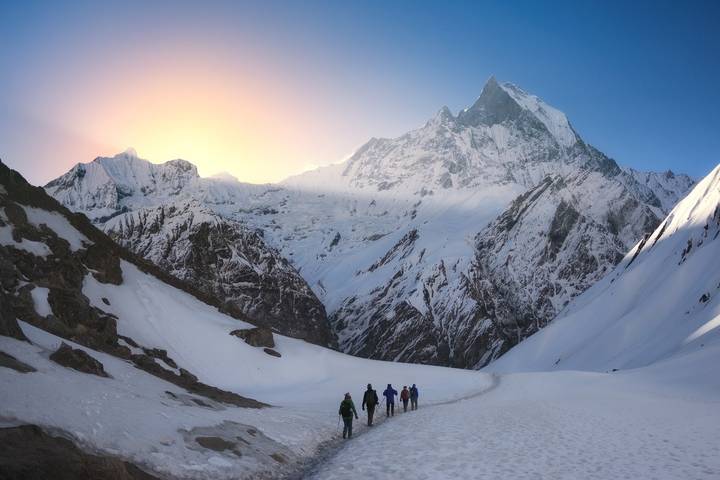 Randonnée en groupe à travers un paysage montagneux enneigé au lever du soleil.