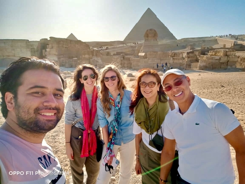 Group of people in front of pyramids, smiling.
