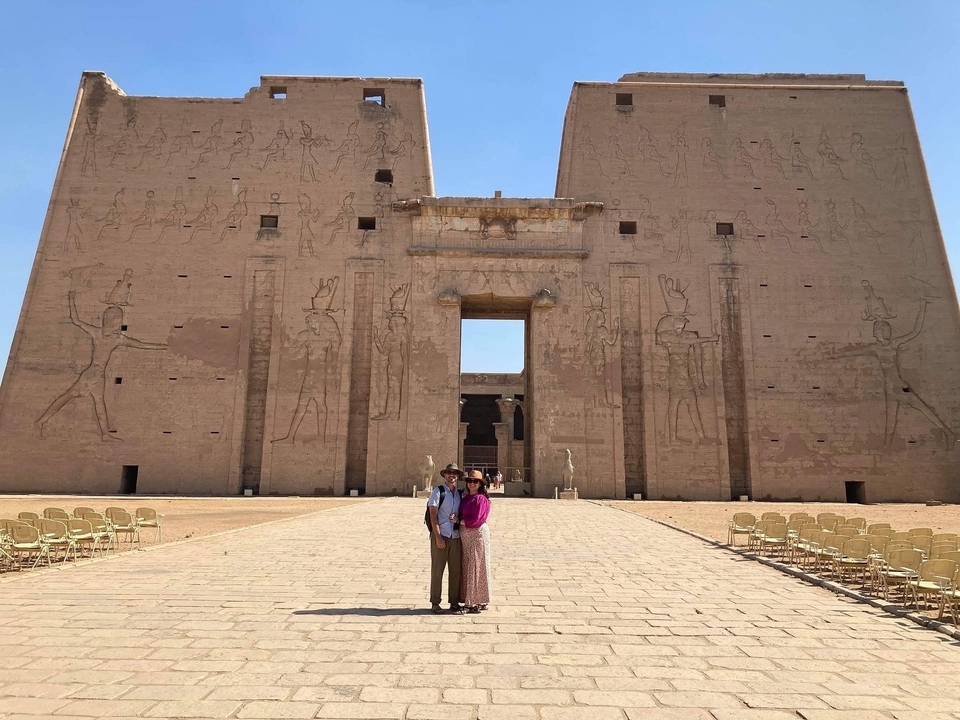 Couple devant un temple égyptien avec des sculptures anciennes.