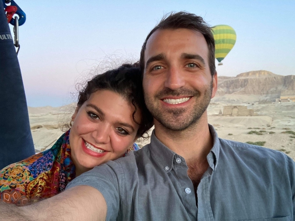 Couple posant avec des montgolfières en arrière-plan.