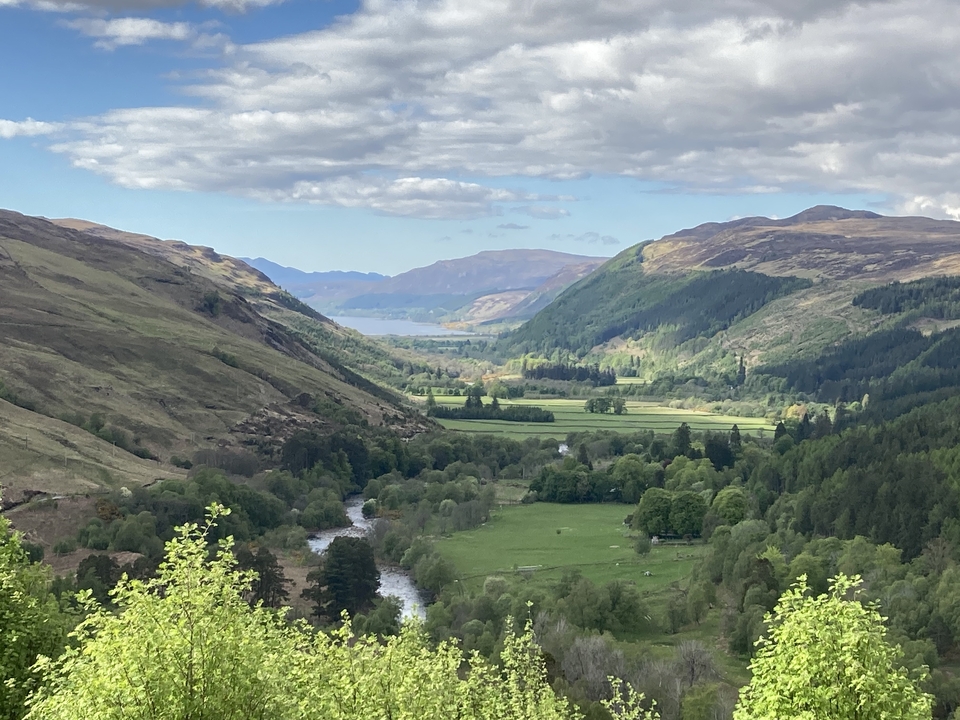Vue panoramique de la vallée avec montagnes lointaines et verdure.