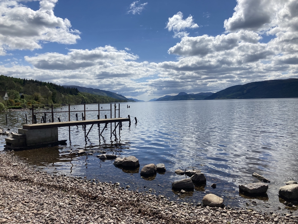 Ponton sur un lac calme avec des collines environnantes.