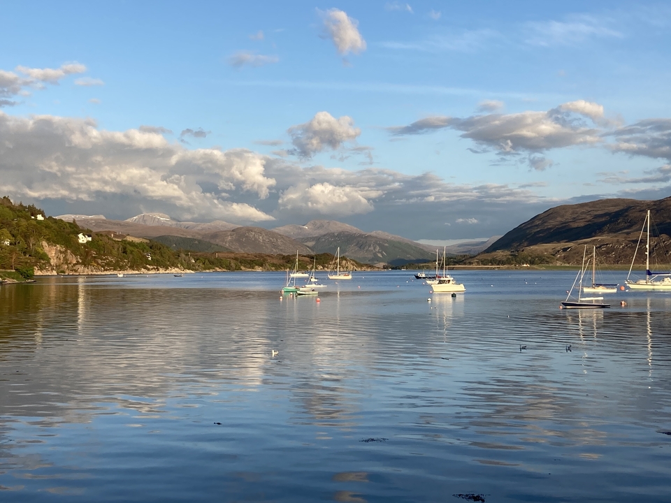 Lac tranquille avec des bateaux et un décor montagneux en arrière-plan.