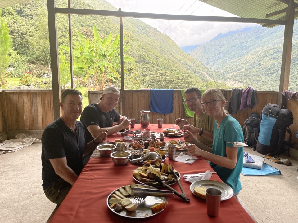 People enjoying a meal on a rustic patio with a view of the valley.